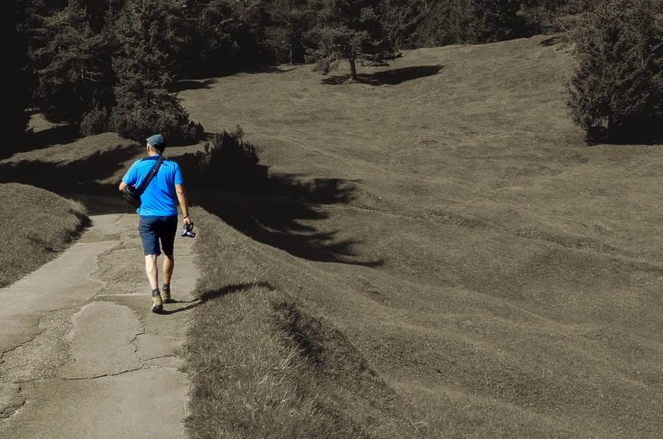 Witek Guziel mit Kamera auf einem Wanderweg über eine Almwiese